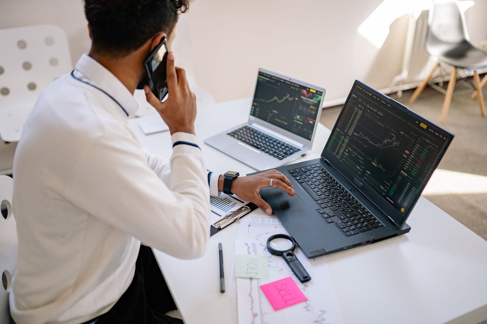 A person contemplating two different laptop models on a desk.