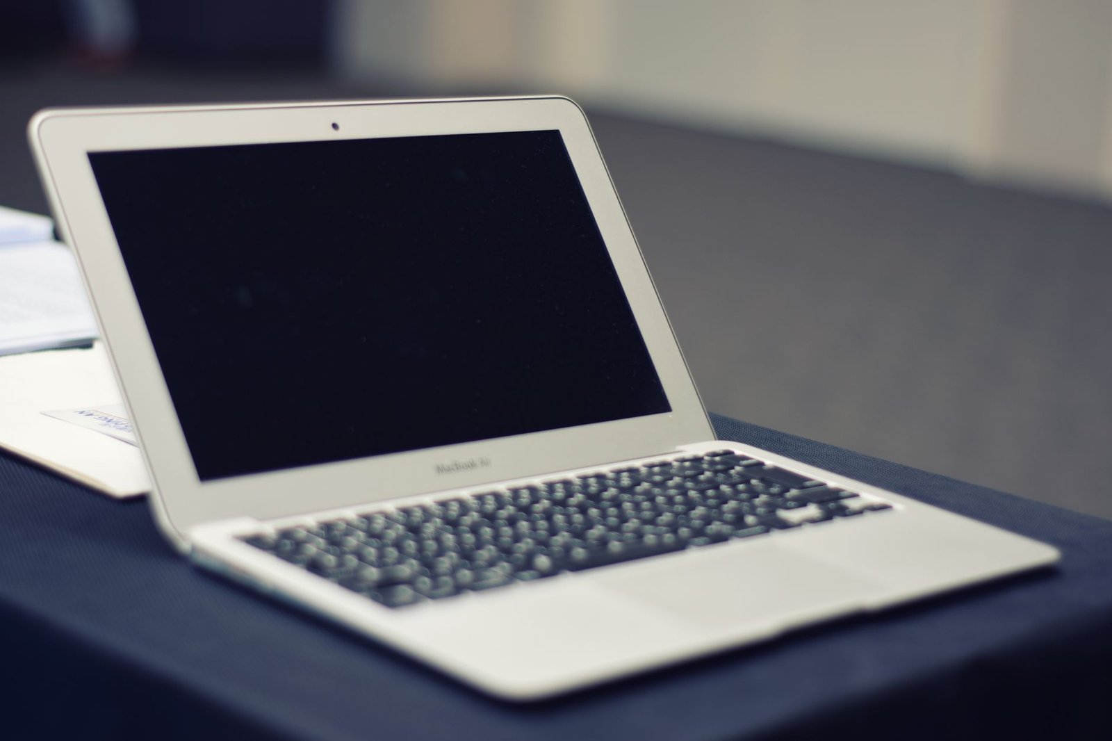 An old, dusty laptop computer sitting on a wooden desk.