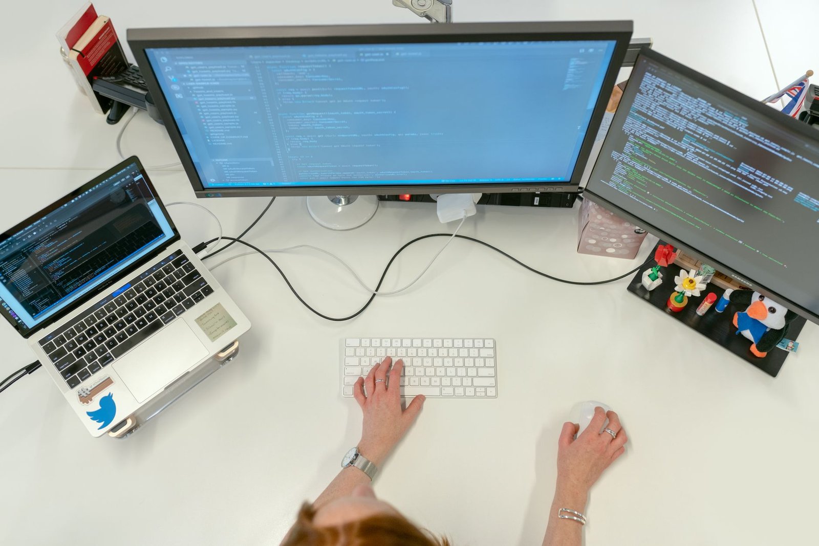 A programmer working on complex code displayed across multiple computer monitors.