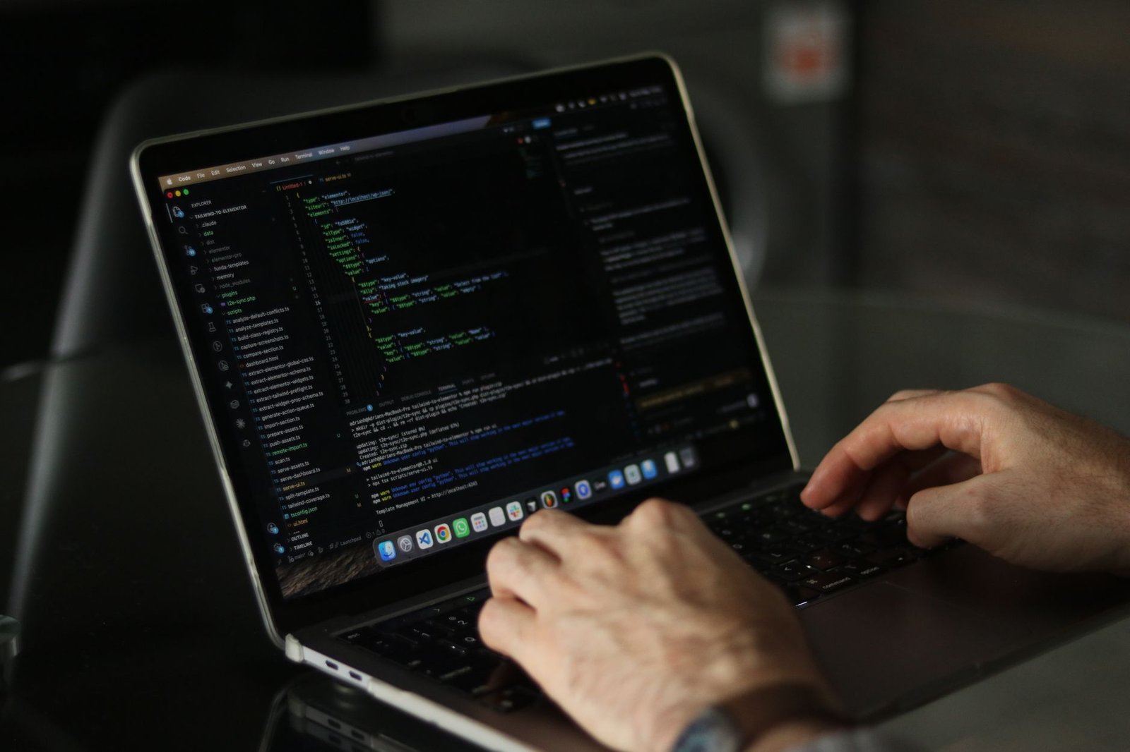 Developer focused on a laptop screen with code editor open.