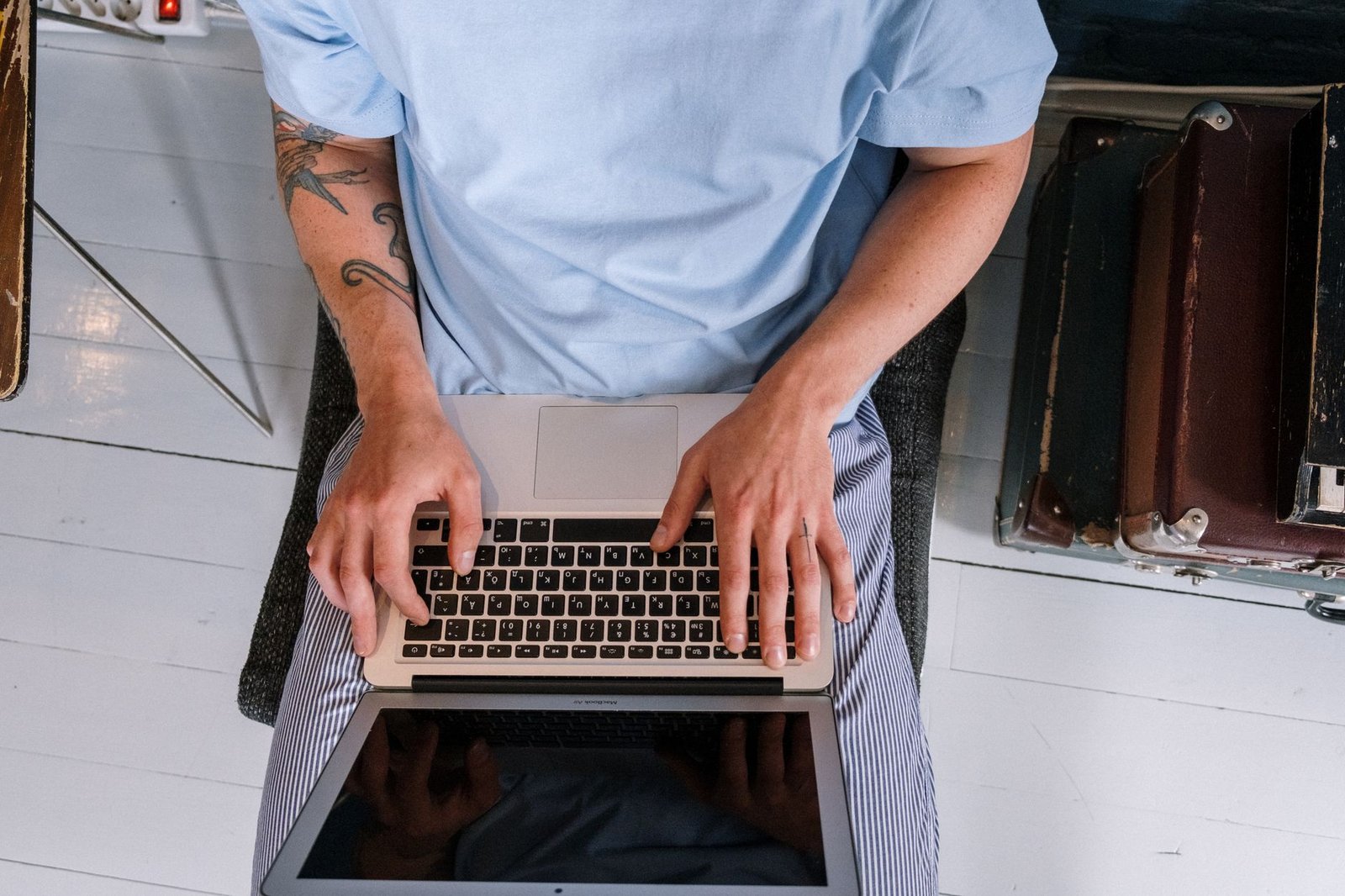 Close-up of a person's hands typing on a vintage laptop keyboard, with the MX Linux Xfce desktop visible on the screen.