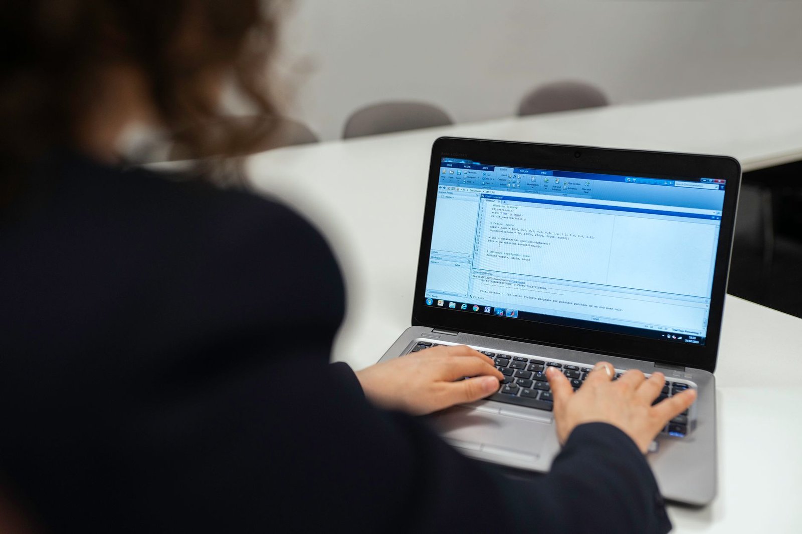 A developer focused on a laptop screen displaying lines of code and AI-related graphics.